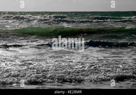 Emerald waves breaking onto the shore in Golden Bay in Malta. Was trying to capture a big fish I saw amidst the waves and caught it silhoutted in a wa Stock Photo