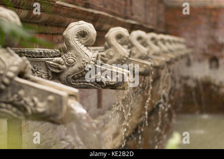 Traditional Nepali water taps shaped like gargoyles, filling a swimming pool in a boutique hotel, Kathmandu, Nepal. Stock Photo