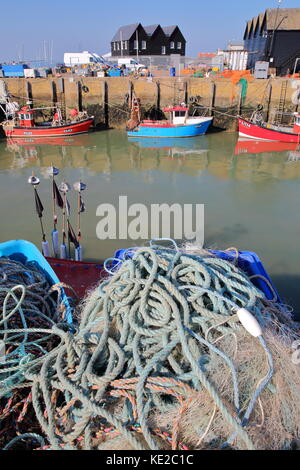 WHITSTABLE, UK - OCTOBER 15, 2017: Close-up on fishing nets at the fishing Harbor with fishing boats and wooden huts in the background Stock Photo