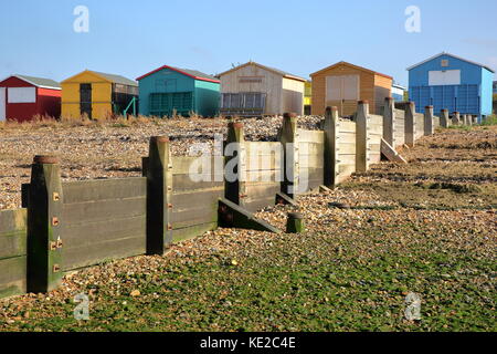 WHITSTABLE, UK - OCTOBER 15, 2017: A row of colorful wooden Huts overlooking the sea with breakwater in the foreground Stock Photo