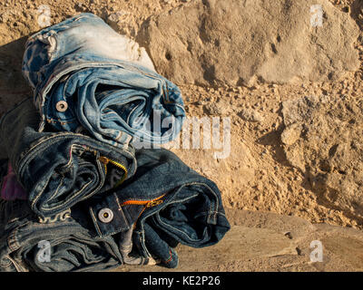 stack of rolled jeans-stone background Stock Photo