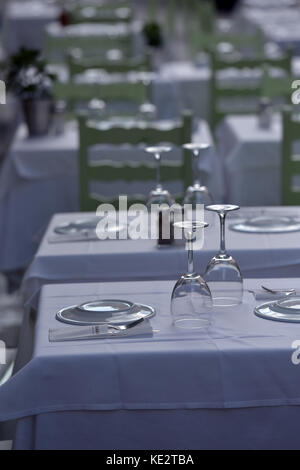 place settings ready for service at a greek tavern or restaurant with glasses, cutlery and white tablecloths. Stock Photo