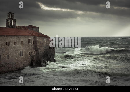 Thunderstorm at  coastline with ancient castle on sea shore with big stormy waves and dark dramatic sky in fall season on sea cost Stock Photo