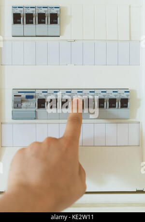 Male hand switching on fuse board. Stock Photo