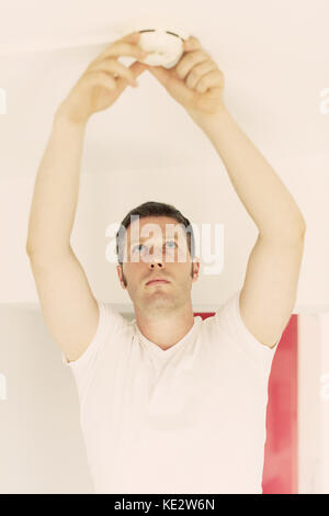 Male technician installing smoke detector at home. Stock Photo