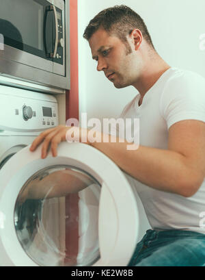 Male technician repairing washing machine at home. Stock Photo