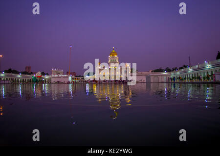 DELHI, INDIA - SEPTEMBER 19, 2017: Beautiful view of the Famous Sikh gurdwara Golden Temple Harmandir Sahib reflected in the artificial pond, with a gorgeous purple sky in India Stock Photo