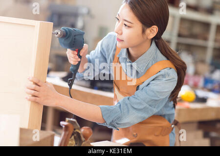 Portrait of young smiling female woodworker using a tool Stock Photo