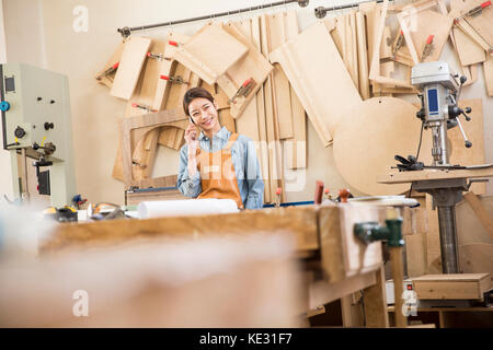 Portrait of young smiling female woodworker talking on cellphone Stock Photo