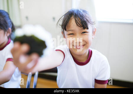 Japanese elementary school kid eating in the classroom Stock Photo