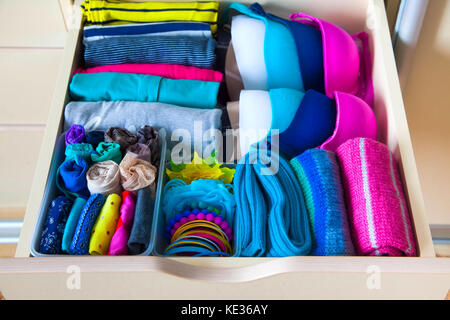 Neatly folded clothes with accessories in chest of drawers Stock Photo