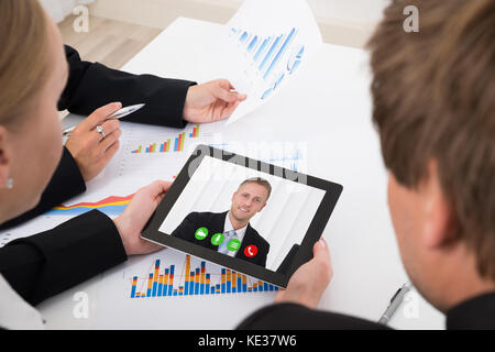 Close-up Of Businesspeople Video Conferencing On Digital Tablet In Office Stock Photo
