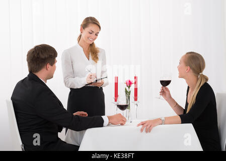 Waitress Taking An Order From A Couple Drinking Glass Of Red Wine Stock Photo