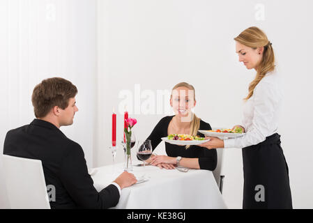Female Couple Serving Food To Young Couple In Restaurant Stock Photo