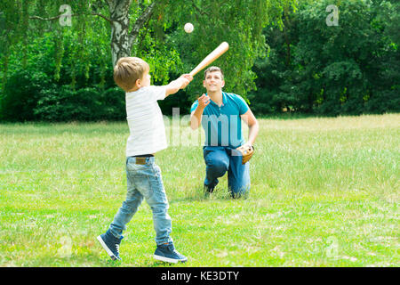 Little Boy Playing Baseball With His Father In Park Stock Photo