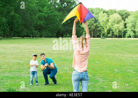 Family Flying The Colorful Kite Together In The Park Stock Photo