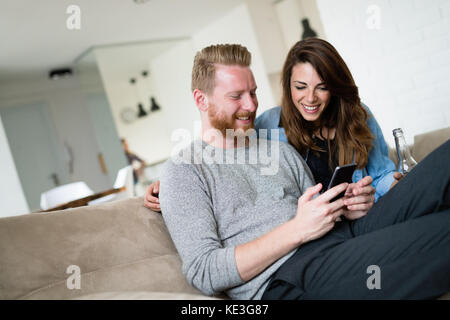 Relaxed couple or friends using mobile phone together to shop online Stock Photo