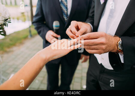 Close-up view of the groom putting the wedding ring on the finger of the bride. Stock Photo