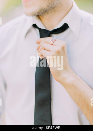 The hands of the man are correcting the black tie. Stock Photo