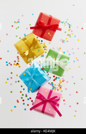 Colorful gift boxes with confetti falling or flying in motion. Stock Photo