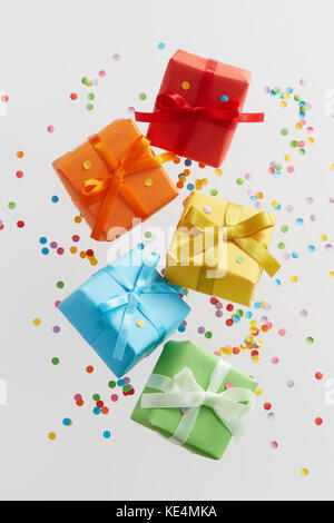 Colorful gift boxes with confetti falling or flying in motion. Stock Photo
