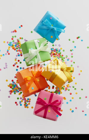 Colorful gift boxes with confetti falling or flying in motion. Stock Photo