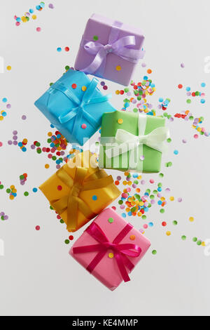 Colorful gift boxes with confetti falling or flying in motion. Stock Photo