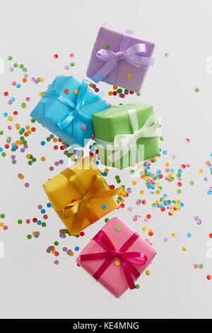 Colorful gift boxes with confetti falling or flying in motion. Stock Photo