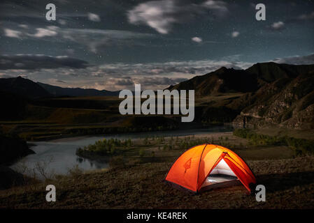 A tent glows under a night sky Stock Photo