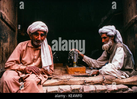 A tailor and his friend, in his shop in the old town of Peshawar, Pakistan Stock Photo