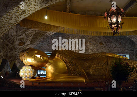 A temple housing one golden reclining Buddha statue. Location is in Mandalay, Myanmar. Pic was taken in August 2015. Stock Photo