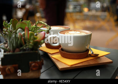 White flat coffee with succulent plant on the table.