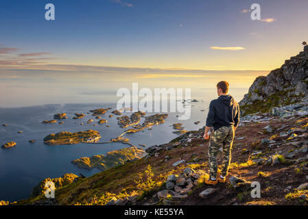 Hiker standing at the top of mount Festvagtinden on Lofoten islands in Norway