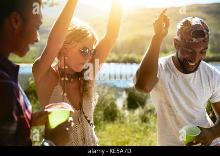 Playful young friends dancing at sunny summer riverside Stock Photo