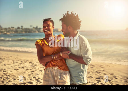 Playful young couple hugging and laughing on sunny summer ocean beach Stock Photo