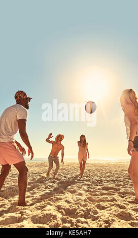 Young friends playing with beach ball on sunny summer beach Stock Photo