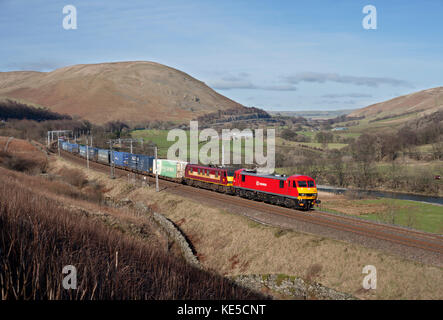 2 DB Cargo class 90 electric locomotives pass through the  Lune Gorge Cumbria  with the 0606 Mossend - Daventry intermodal container freight train Stock Photo
