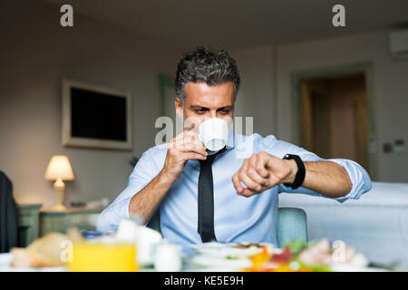 Mature businessman having breakfast in a hotel room. Stock Photo