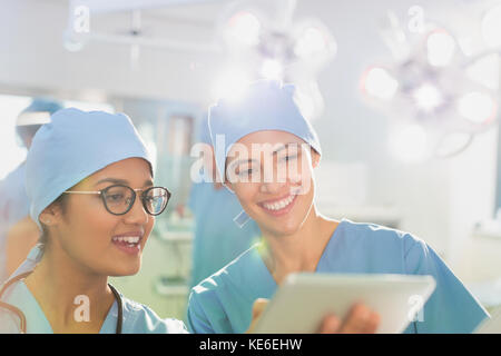 Female surgeons using digital tablet, talking in operating room Stock Photo