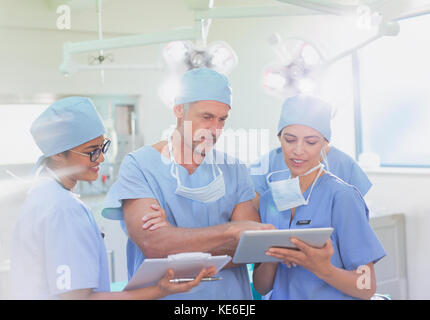 Surgeons and nurse using clipboard and digital tablet in operating room Stock Photo
