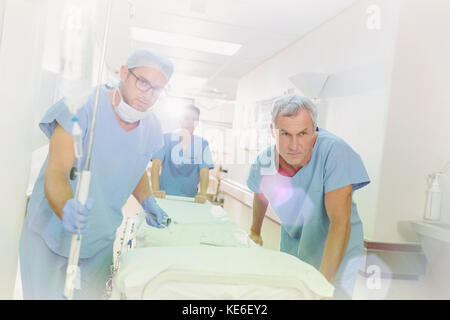 Determined surgeons pushing stretcher down hospital corridor Stock Photo