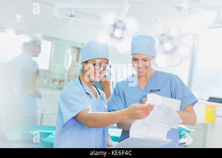 Female surgeons reviewing paperwork in operating room Stock Photo