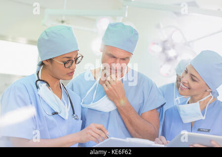 Surgeons reviewing paperwork in operating room Stock Photo