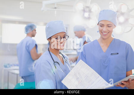 Female surgeons reviewing paperwork in operating room Stock Photo