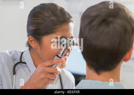 Female doctor using otoscope in ear of patient Stock Photo
