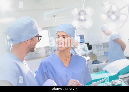 Smiling surgeons talking in operating room Stock Photo
