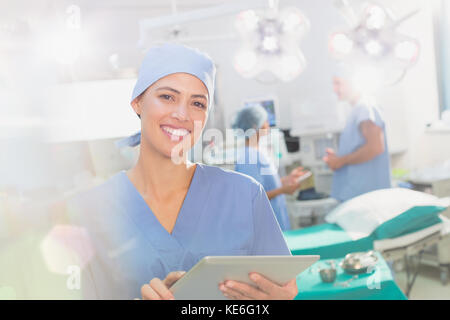 Portrait smiling, confident female surgeon using digital tablet in operating room Stock Photo