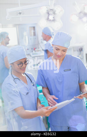 Female surgeons reviewing clipboard paperwork in operating room Stock Photo