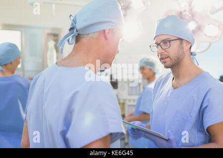 Male surgeons with digital tablet talking in operating room Stock Photo