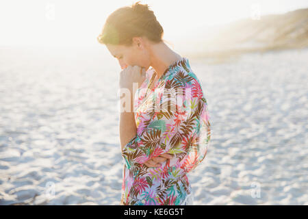Serene brunette woman in swimsuit coverup on sunny summer beach Stock Photo